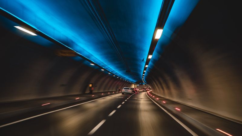 De binnenkant van een tunnel met enkele auto's die er rijden.