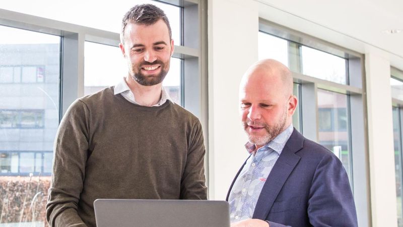 Two people are working on a laptop together.