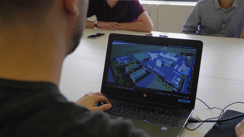 Je kijkt over de schouder van een man die een visualisatie van een terrein bekijkt op zijn laptop.