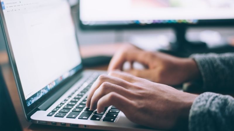 2 handen die aan het typen zijn op een laptop.
