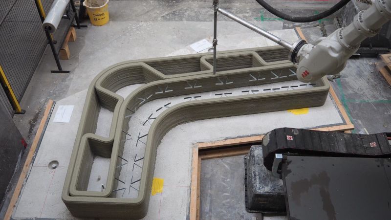 A photo of a 3D concrete printer. The printer is working.