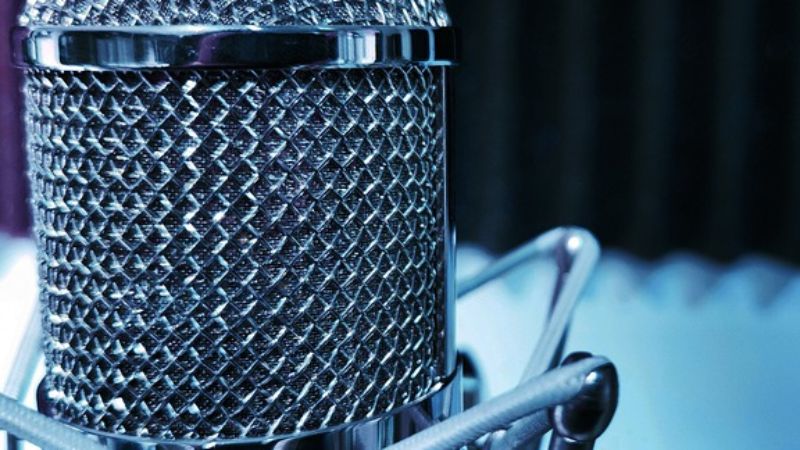 A photo of a microphone in front of a blue background.