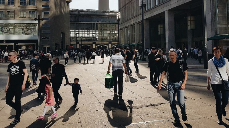 Many people walk across a square in the city.