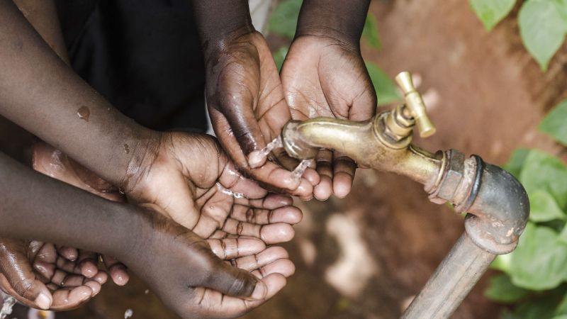 A photo of small hands washing their hands under a water tap.