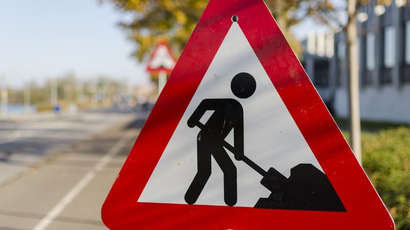 Een driehoekig verkeersbord met rode rand. Het bord zegt dat er wegwerkzaamheden zijn.
