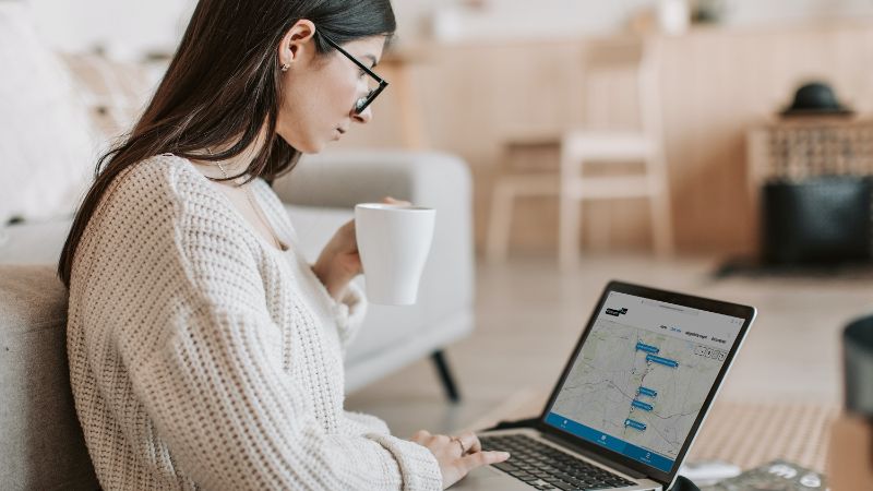 Een vrouw met haar laptop op haar schoot. Ze kijkt naar haar scherm waarop een InBeeld omgeving is te zien.