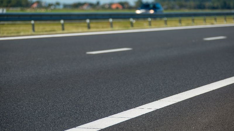 A photo of the asphalt with white lines of a highway.