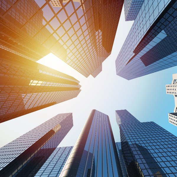 A photo taken from the ground up in the air. You can see the sun and buildings. 