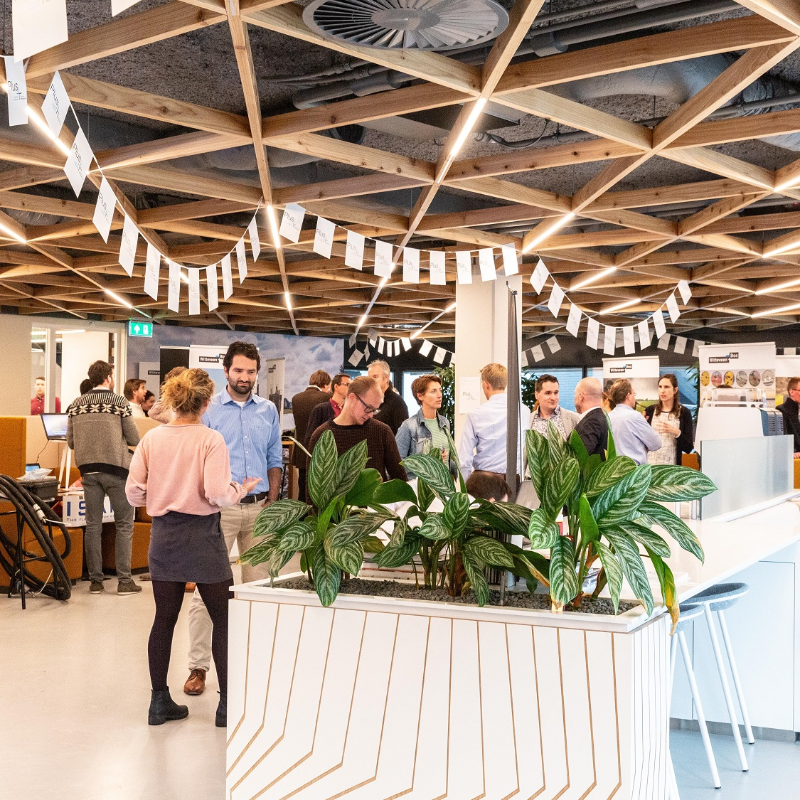 Foto van de lobby van hoofdkantoor Deventer. Collega's komen samen en staan in kleine groepen met elkaar te praten.
