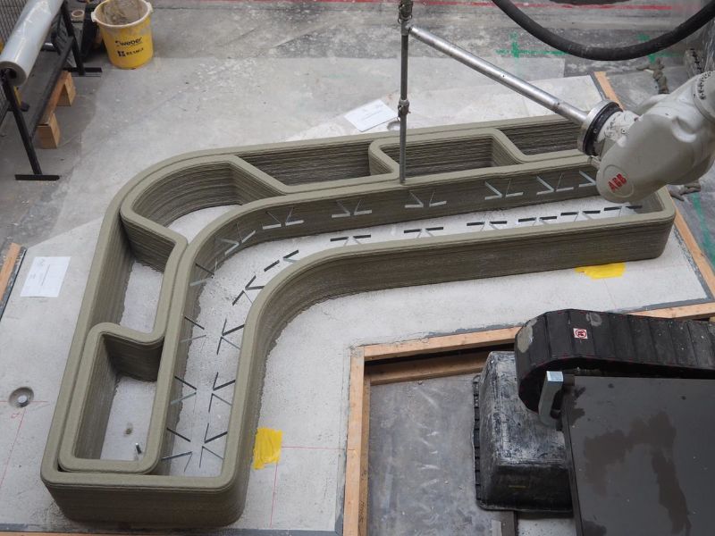 A photo of a 3D concrete printer. The printer is working.