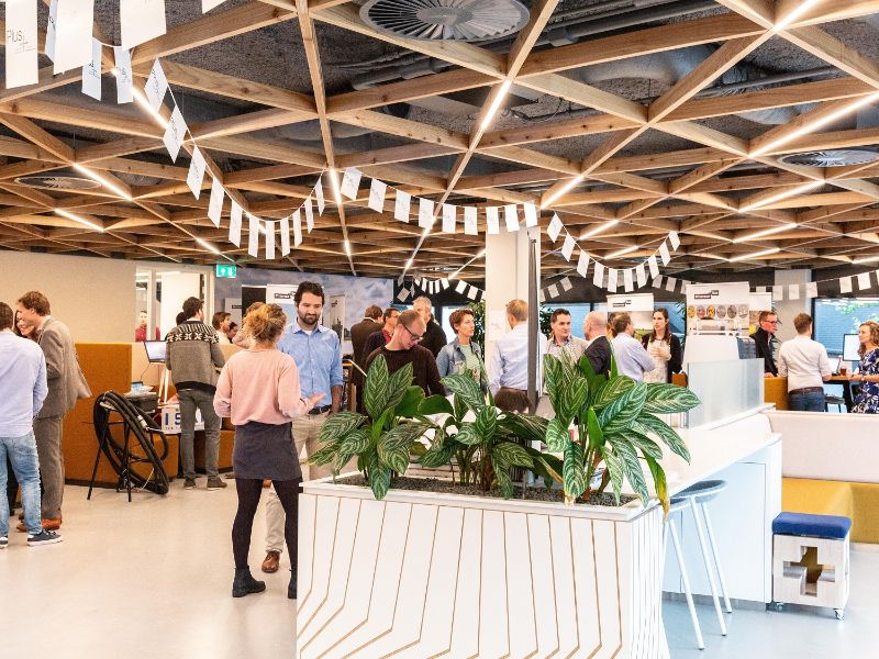 Picture of our lobby of the head office in Deventer, the Netherlands. Colleagues are having a gathering and are chatting with each other in small groups, while standing up.