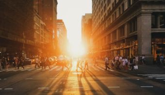 Een foto waar je de zon ziet tussen gebouwen in de stad.